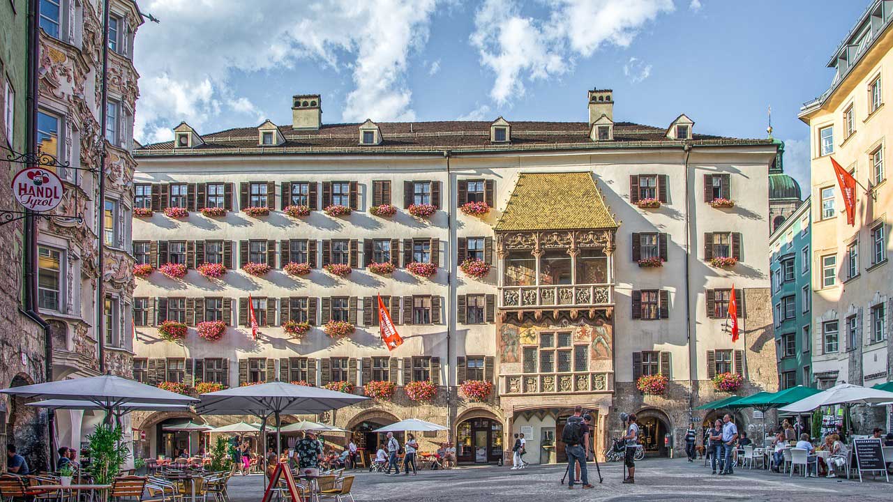 cafe city center in innsbruck with people outside drinking coffee and a golden tin roof building around the world top 5 with blue skies