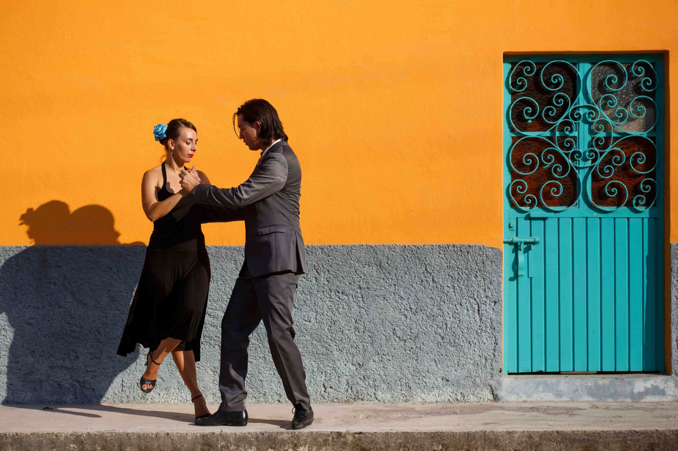 male and female dancing tango with orange background and green door