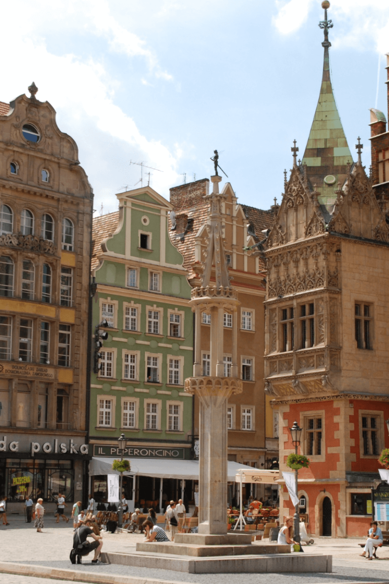 european city this is warsaw in poland center square with buildings and people walking clear blue skies