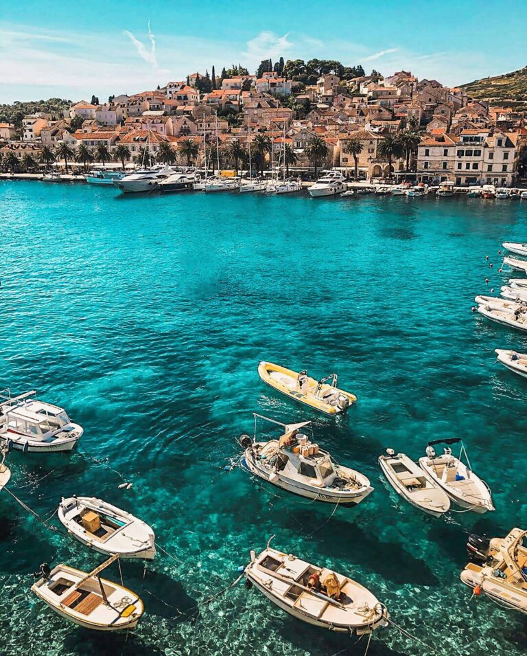 crystal clear blue lagoon overlooking mountains on the coast of croatia with small tug boats floating on the water