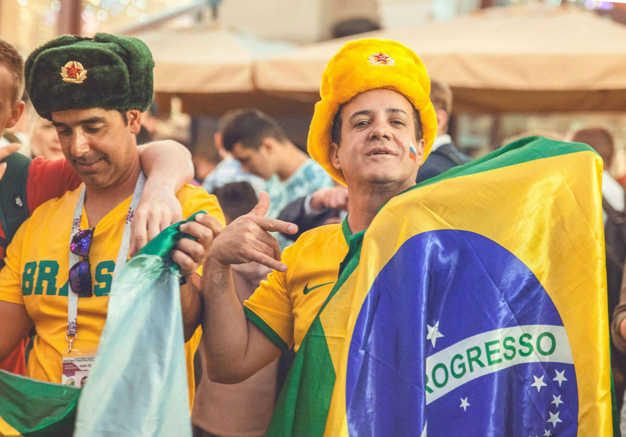 two brazilian men holding up yellow and green brazil flag